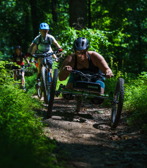Image of athlete riding an adaptive bike on a natural surface trail